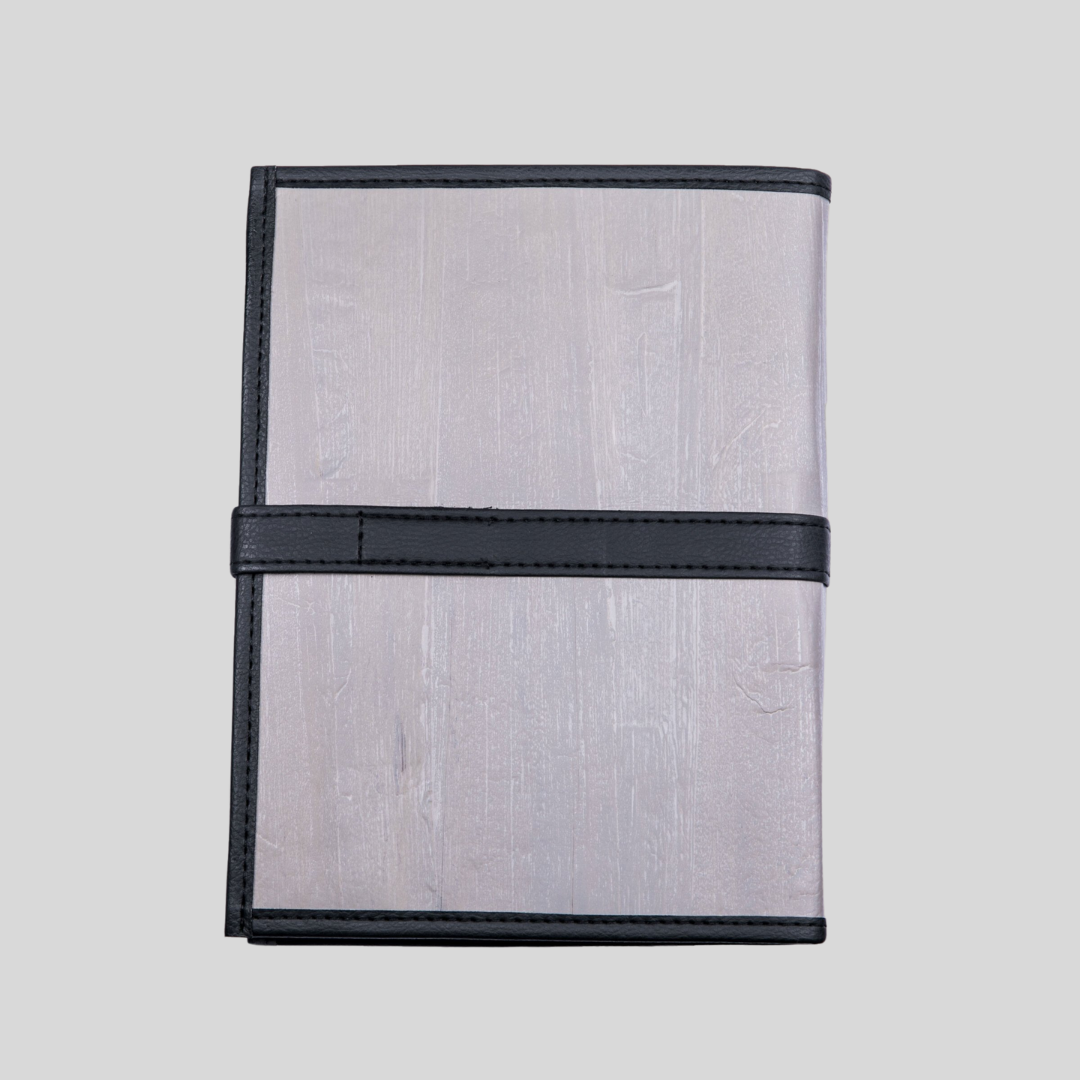 The back side of a coal gray vegan leather journal with dark gray hem and belt buckle closure that wraps around the journal.