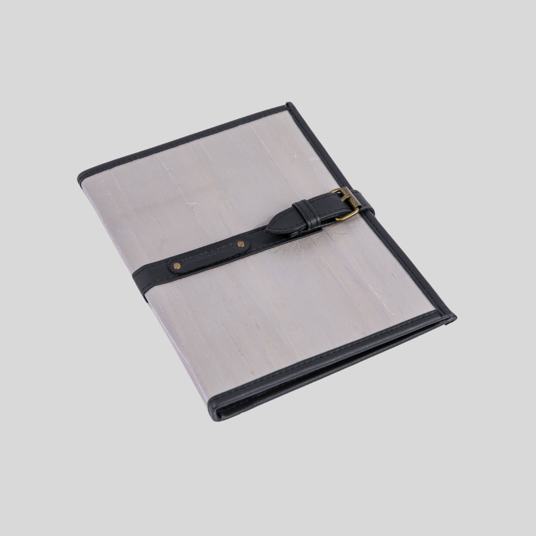 A light gray journal made of vegan leather, with a faux belt buckle closure strap.
