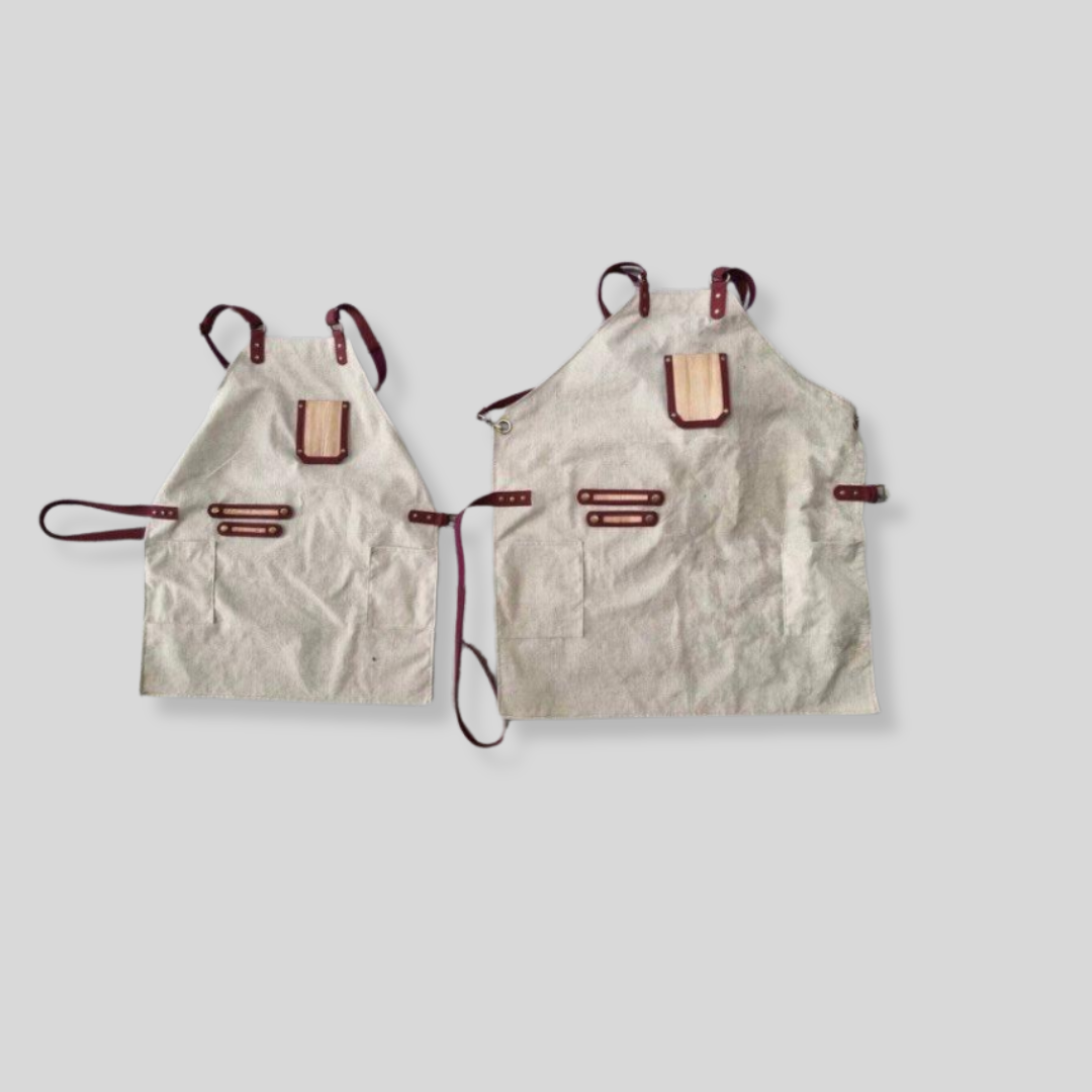 Two matching cream-colored aprons with red leather accents that compliment the fabric color.