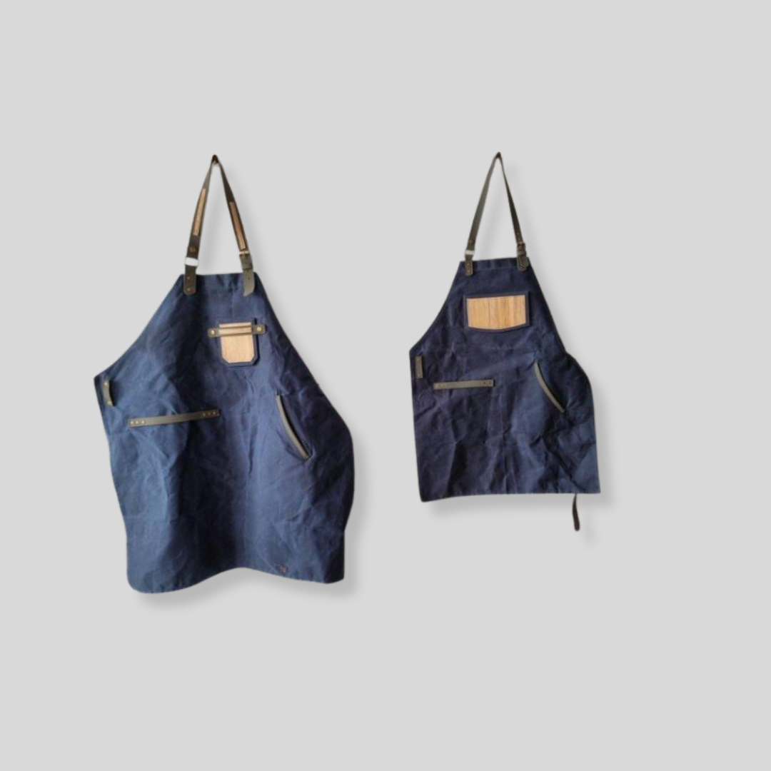 Two matching dark blue aprons that have vegan leather chest pockets.