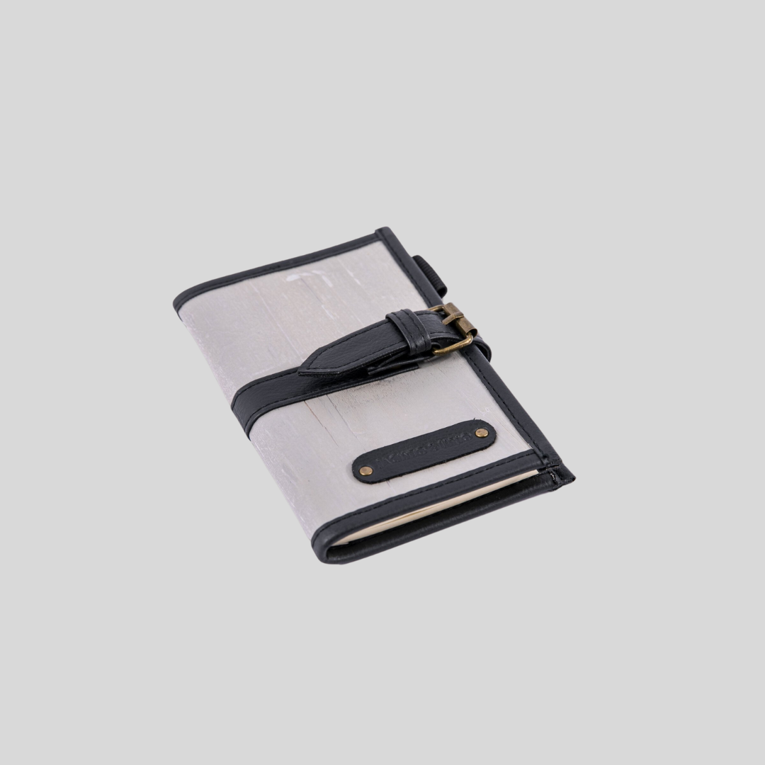 A light gray vegan leather journal with dark gray leather hemming.