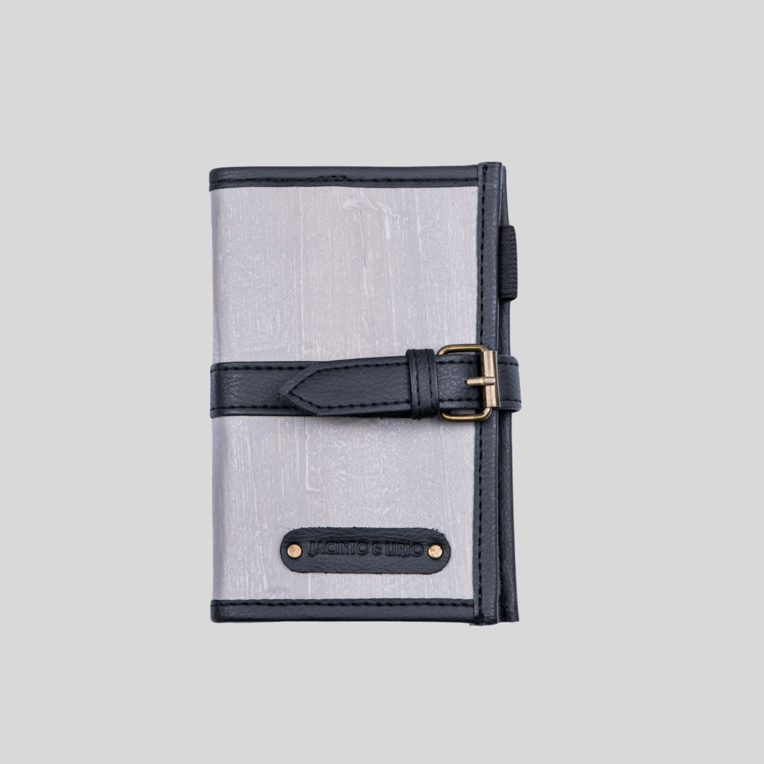 A gray leather notebook that has a gray belt closure, giving it a rustic aesthetic.
