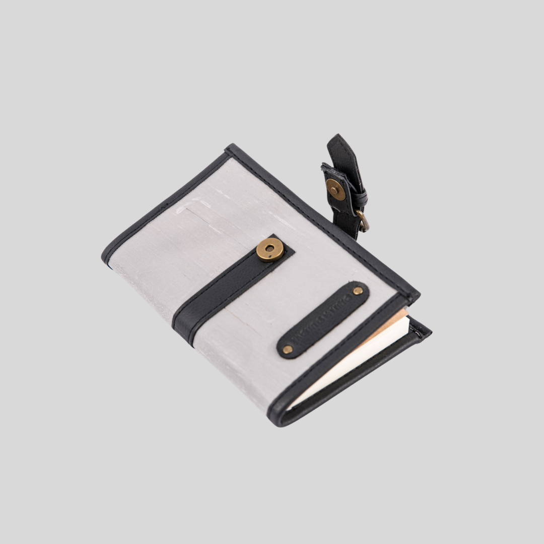 A small vegan leather masculine notebook lies on its back and opened.