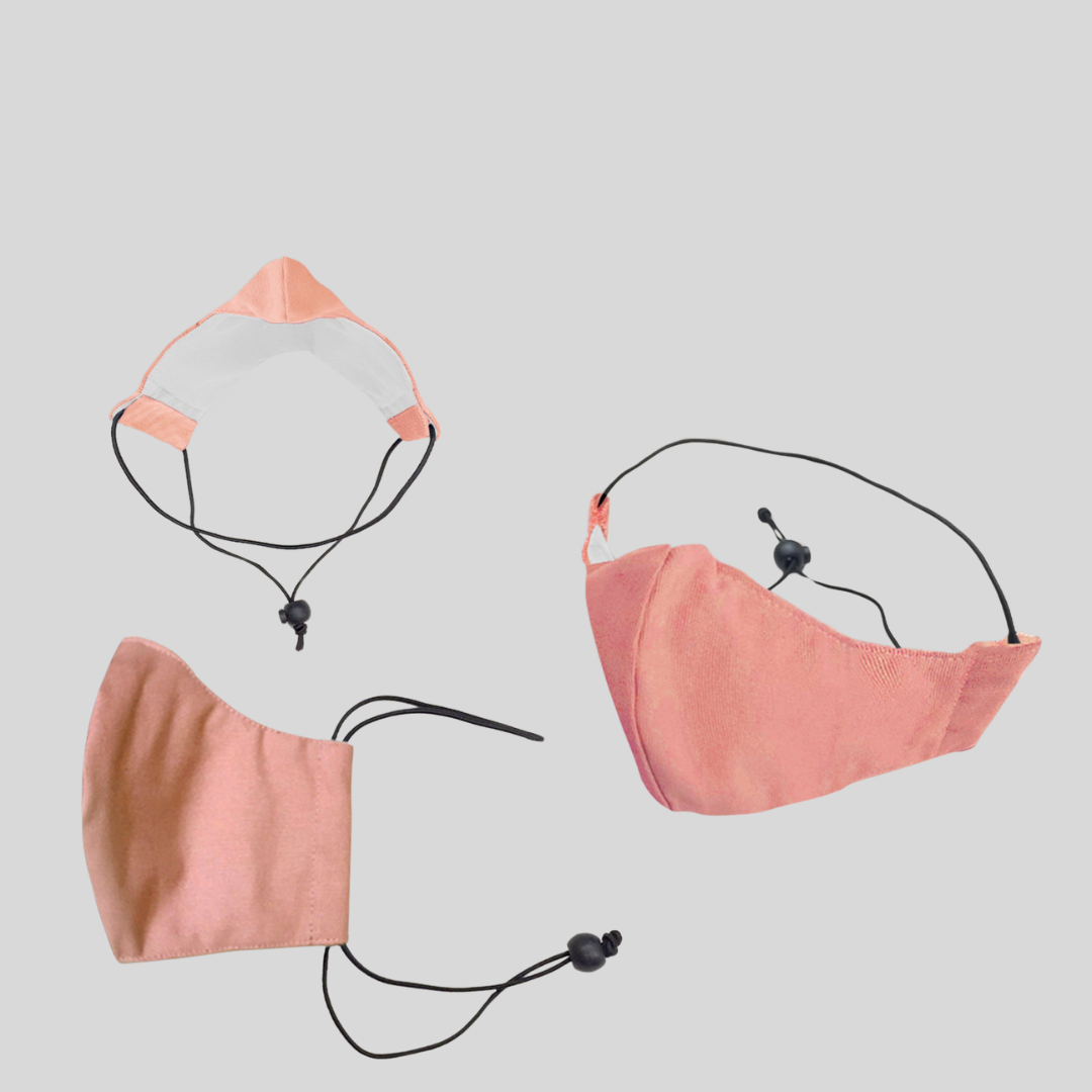 three angles of a pastel pink fabric surgical mask with a drawstring toggle on the lower straps for security.