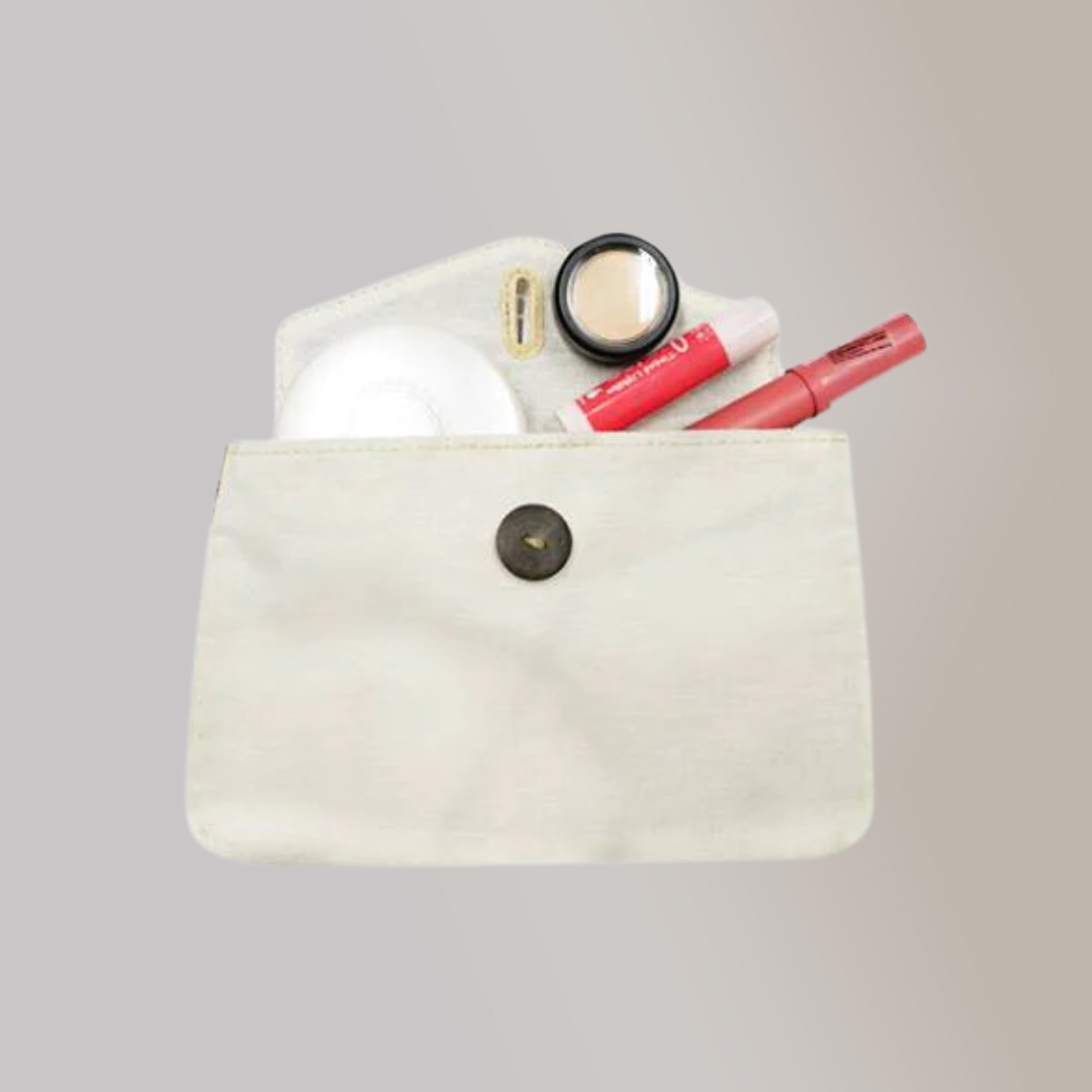 Top view of a white canvas pouch with a black button containing various makeup products.