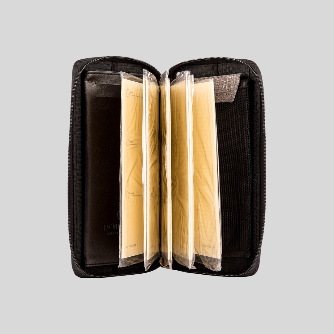 A zippered notebook in a dark color has page inserts with plastic packaging in it.
