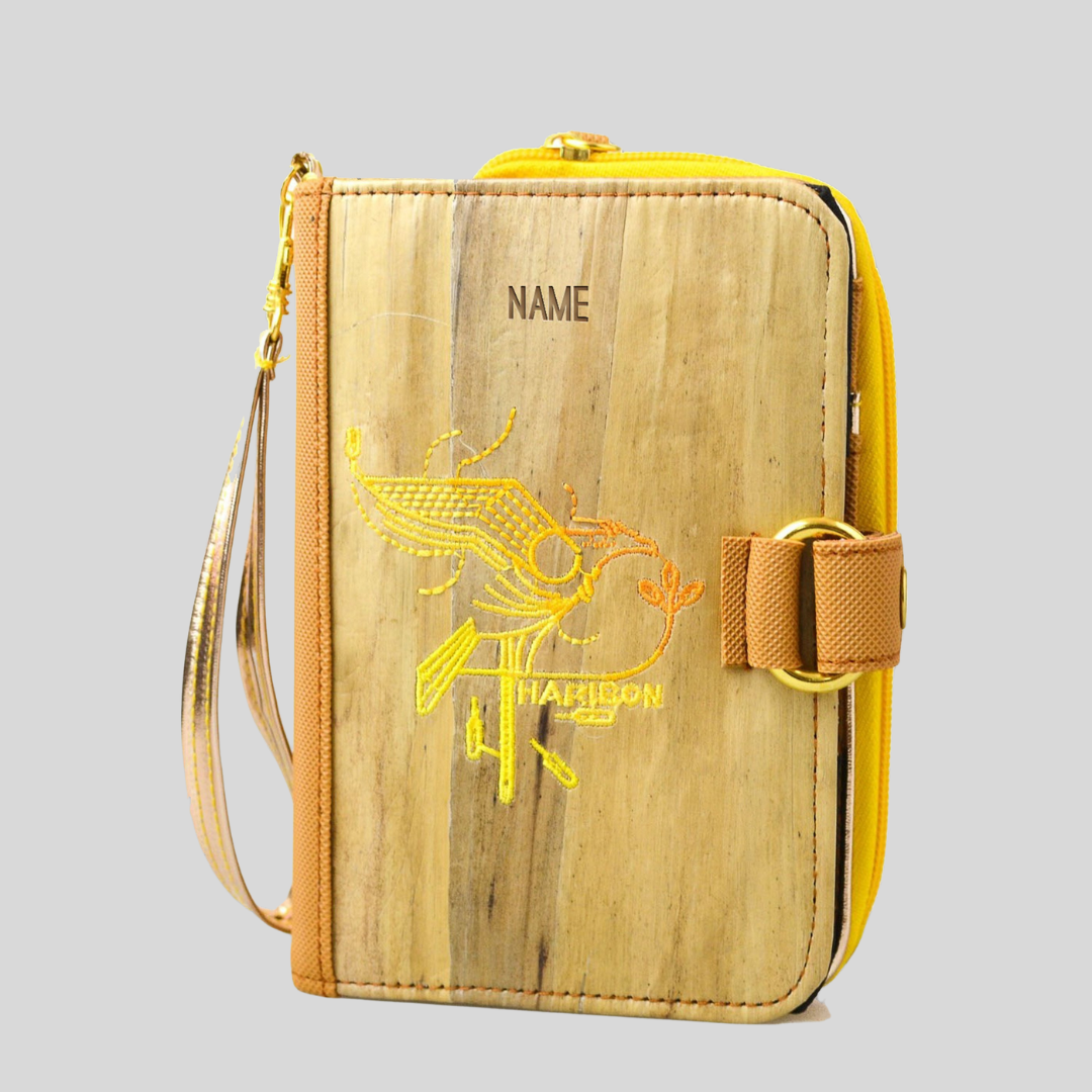 A vibrant yellow vegan leather notebook with built-in wallet that has an embroidered yellow design on its cover.