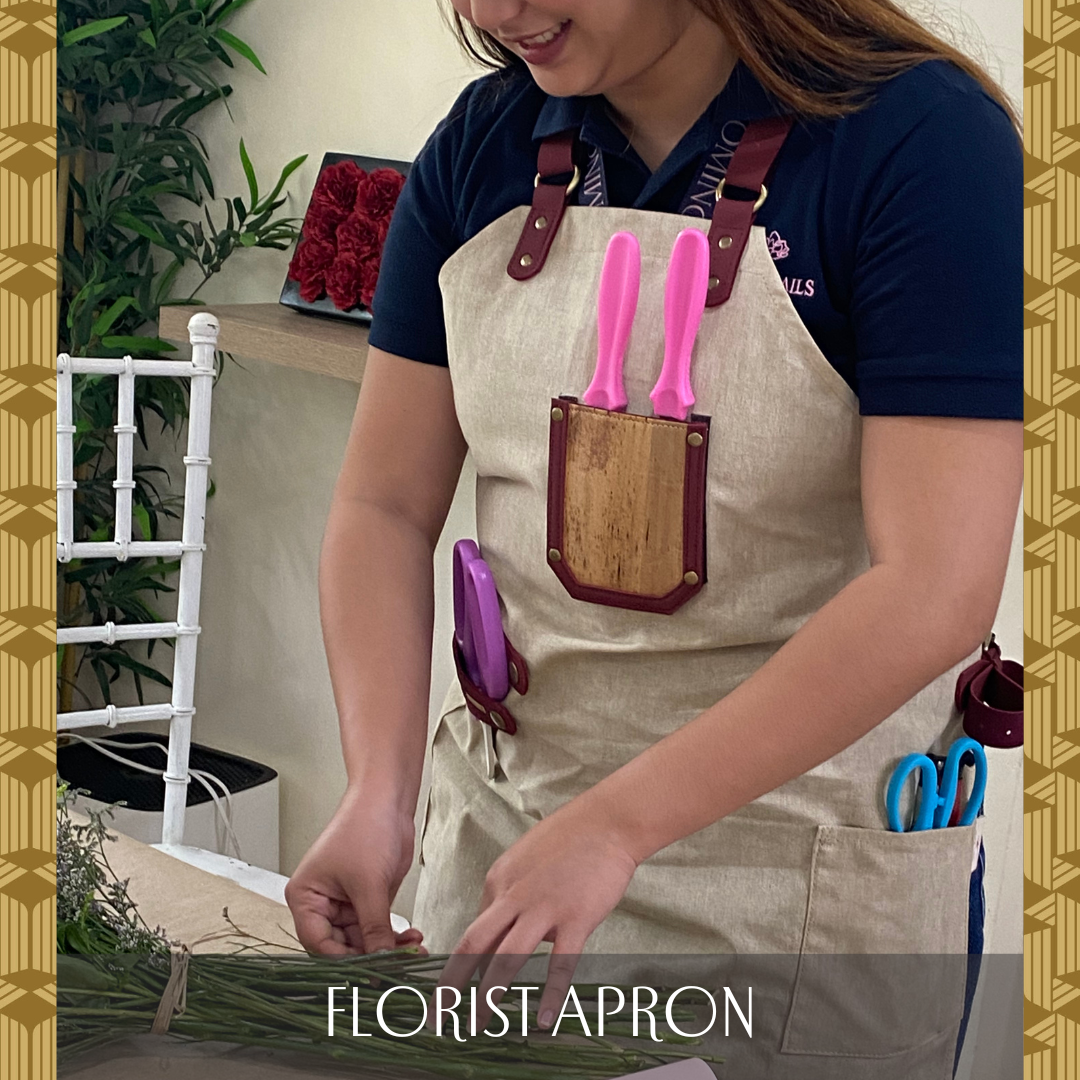Sustainable apron made out of vegan leather with 3 different pockets being used by a florist to store shears and equipment as they tie up flowers.