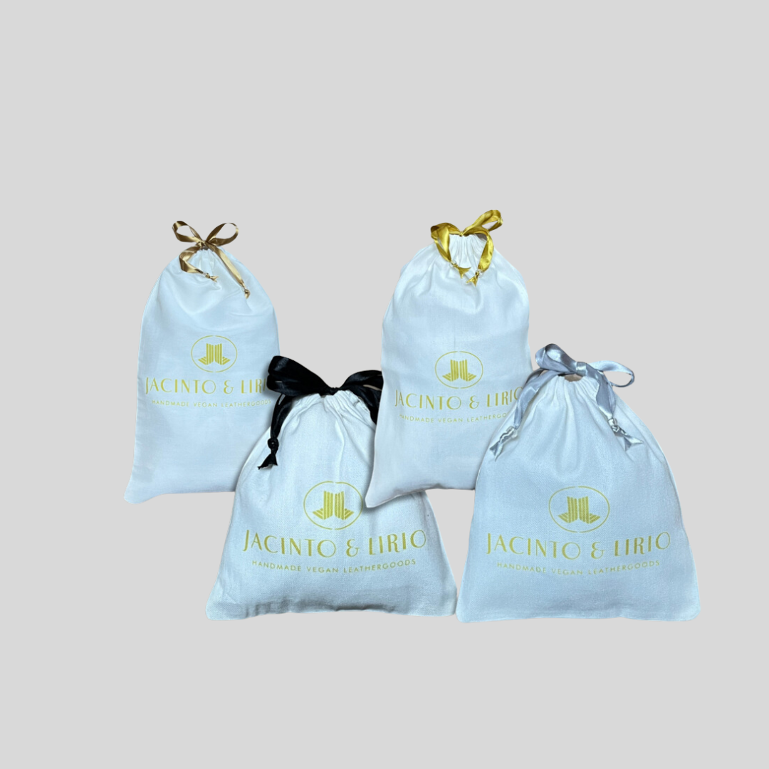 drawstring eco-bags with a white fabric design, different color ribbon closures, and branding for handmade vegan leathergoods.