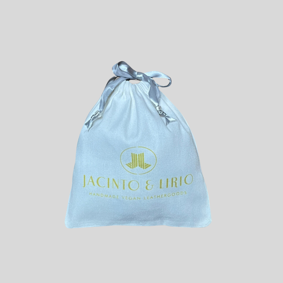 drawstring eco-bag with a white fabric design, silver ribbon closure, and branding for handmade vegan leathergoods.