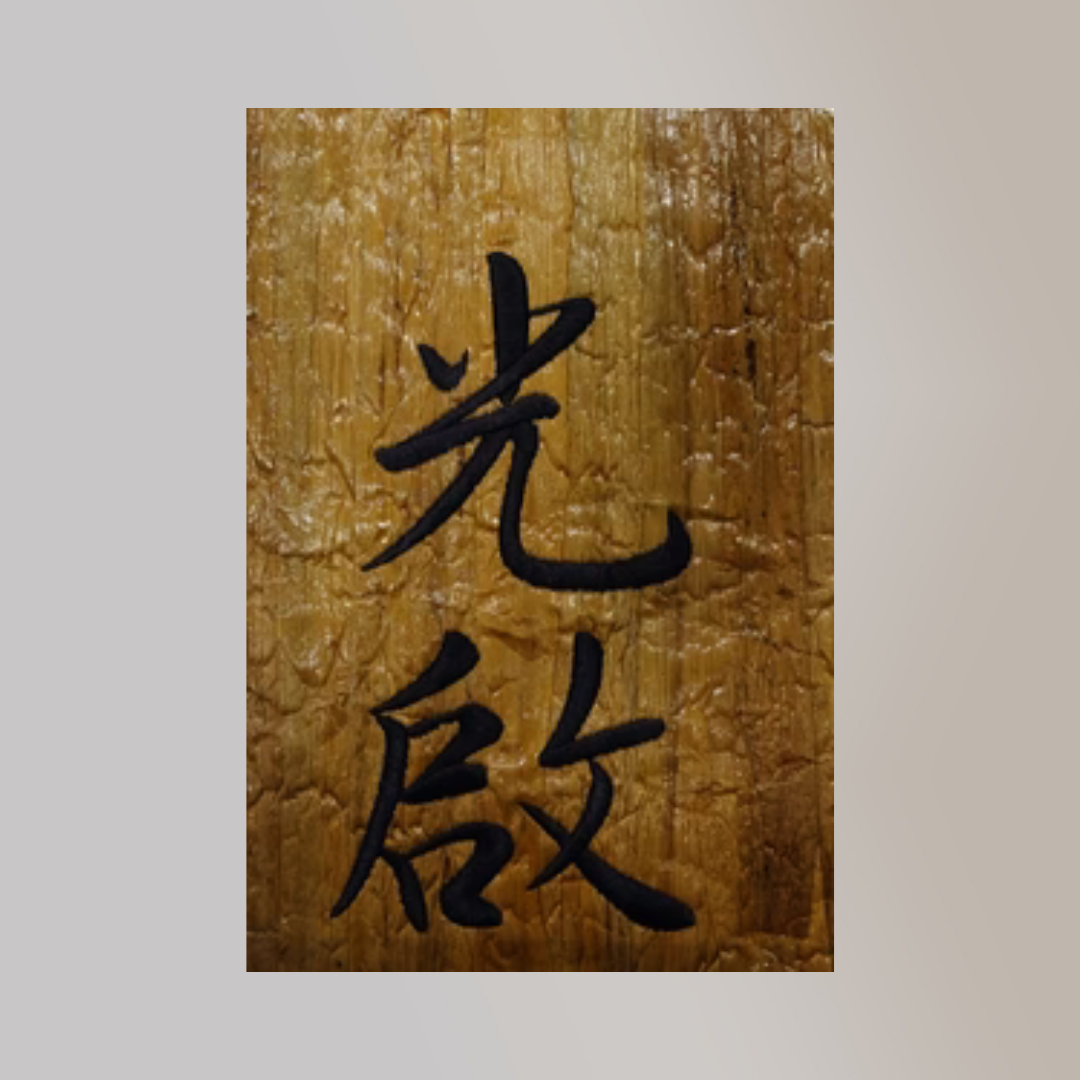 opaque black embroidered mandarin text on a piece of wrinkled vegan leather made of water hyacinth.