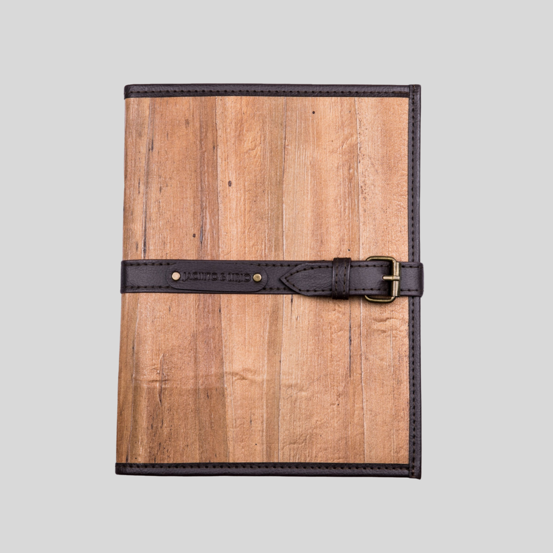 A brown vegan leather encased notebook with a slim dark brown belt buckle closure, giving a vintage, masculine feel.