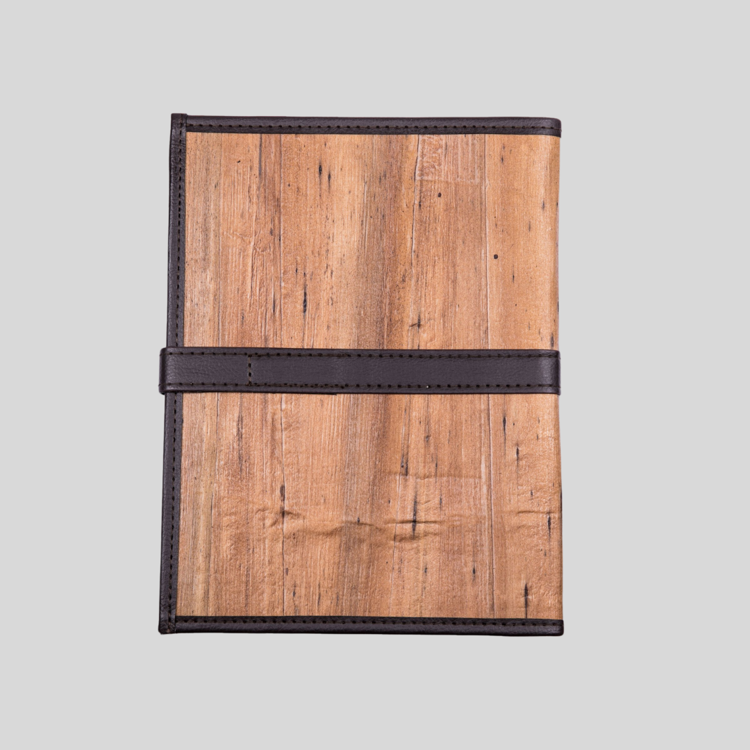 The back of a vegan leather notebook with dark brown leather hemming and a strap for closure.