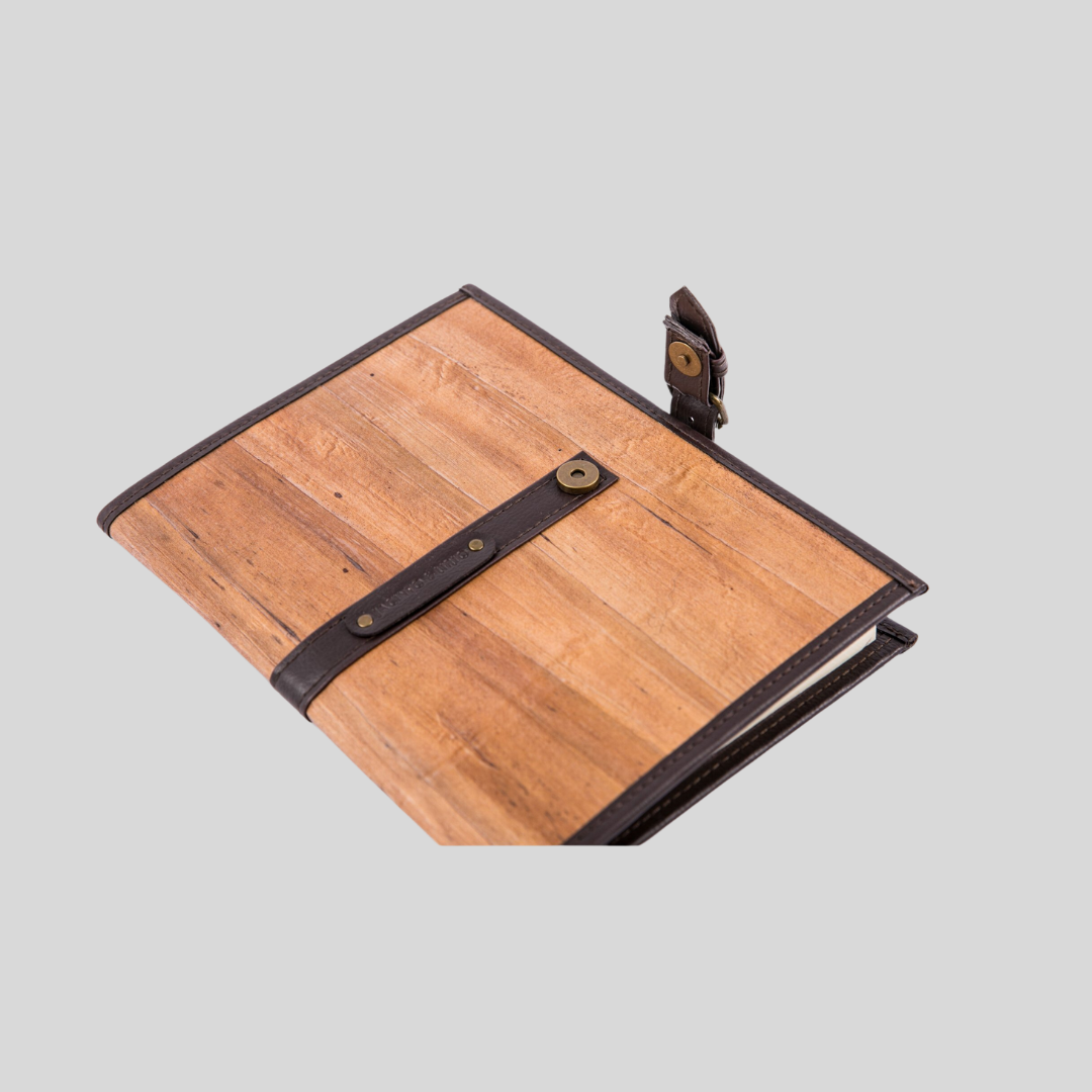 A rustic notebook made out of vegan leather, with an unlatched belt buckle closure.