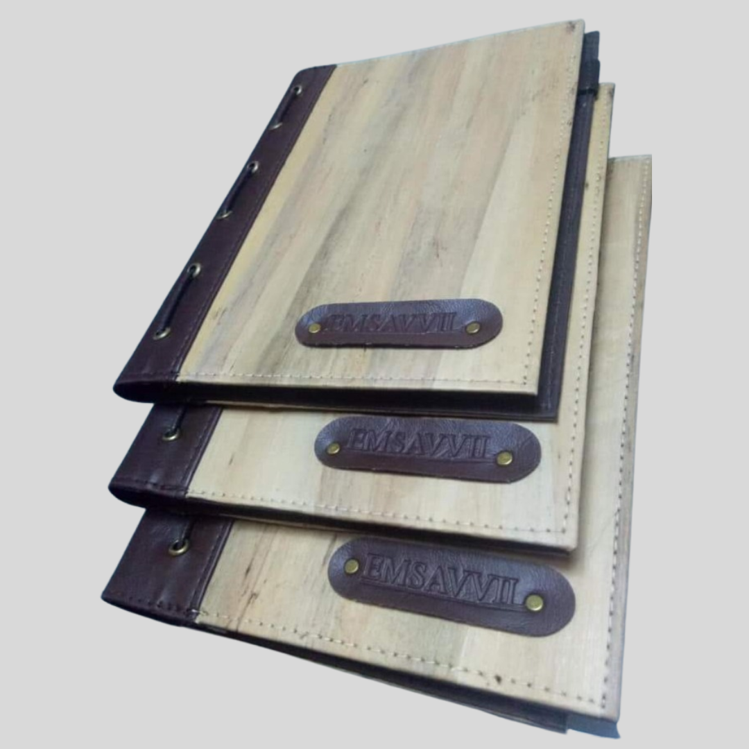 three vegan leather notebooks with a custom dry-embossed name in the lower corner, on a tab of dark brown leather.