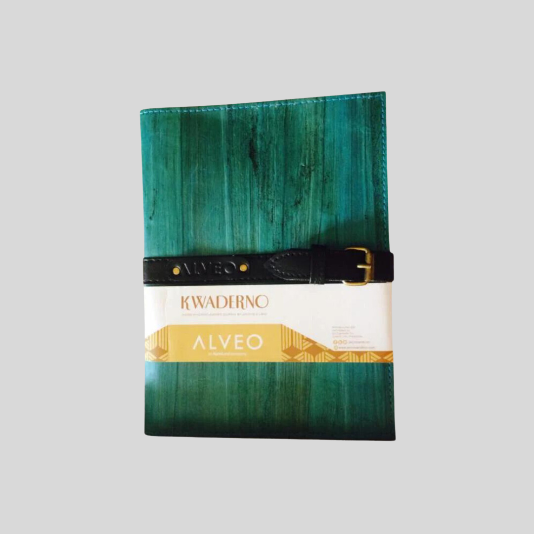 A teal-green vegan leather notebook with an embossed name on its jet black belt buckle closure.