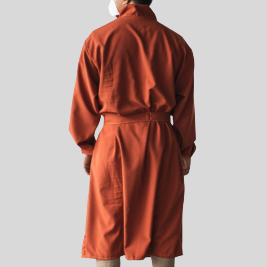 The posterior view of a person wearing an orange water-repellant PPE suit that looks like a trench coat.