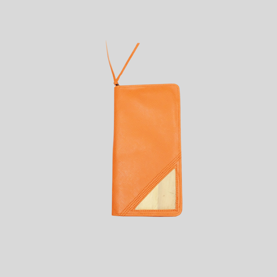 An orange purse with a wristlet and a triangular piece of water hyacinth vegan leather in the bottom right corner.