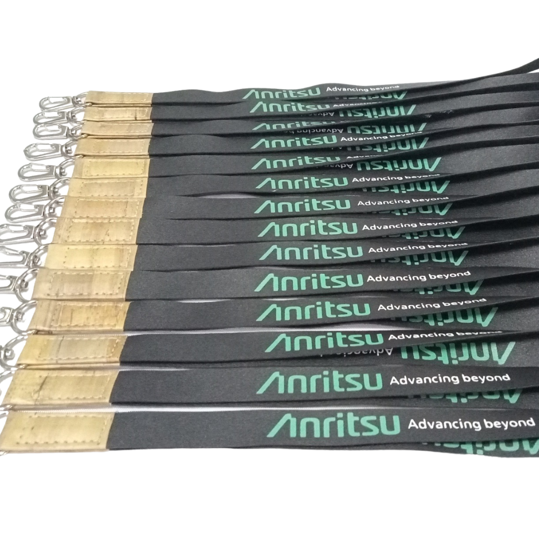 Multiple black Anritsu branded lanyards laid side-by-side, each featuring green "Anritsu Advancing Beyond" text, a light brown faux vegan leather accent, and a silver swivel clip. Ideal for corporate branding and event identification.