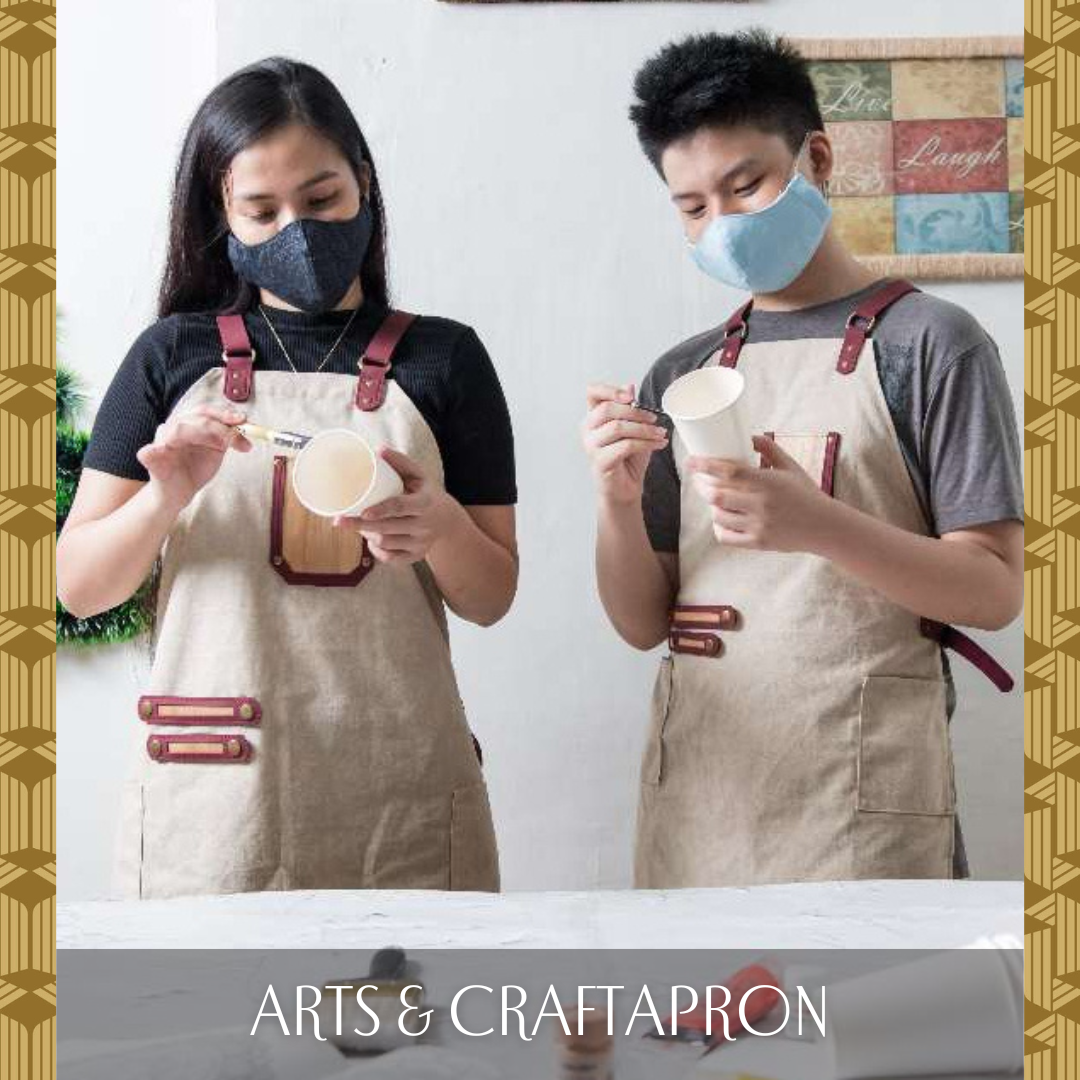 Two people weraring a cream colored apron with vegan leather accents and red leather straps and hemming, whilst painting cups.