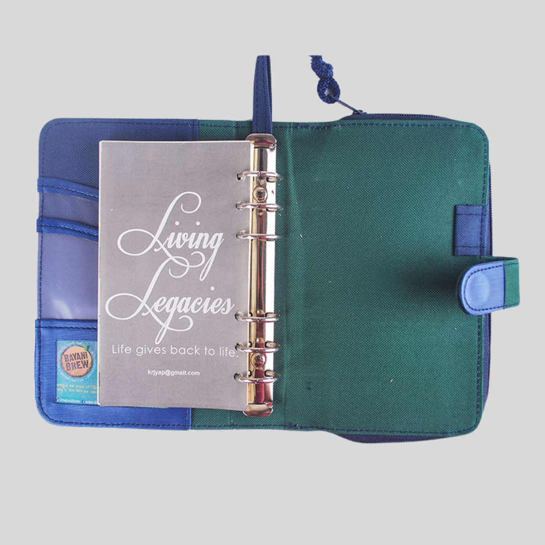 Company logo printed on last page of a refillable blue leather notebook that has a metal spine and a card holder in its inner sleeve.