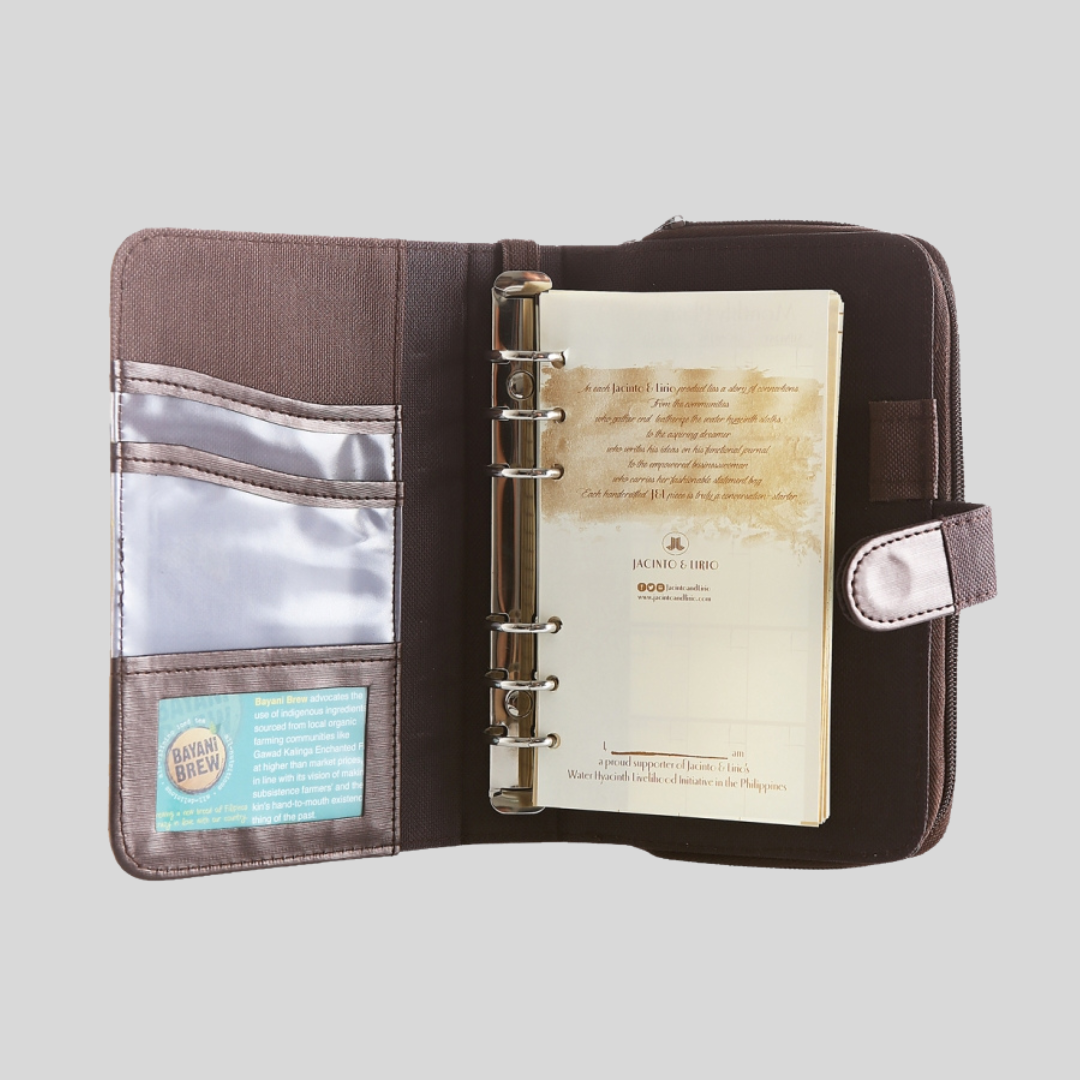 A brown leather notebook opened to its first page with writing on it and its inside flap which has card and picture compartments in clear plastic.