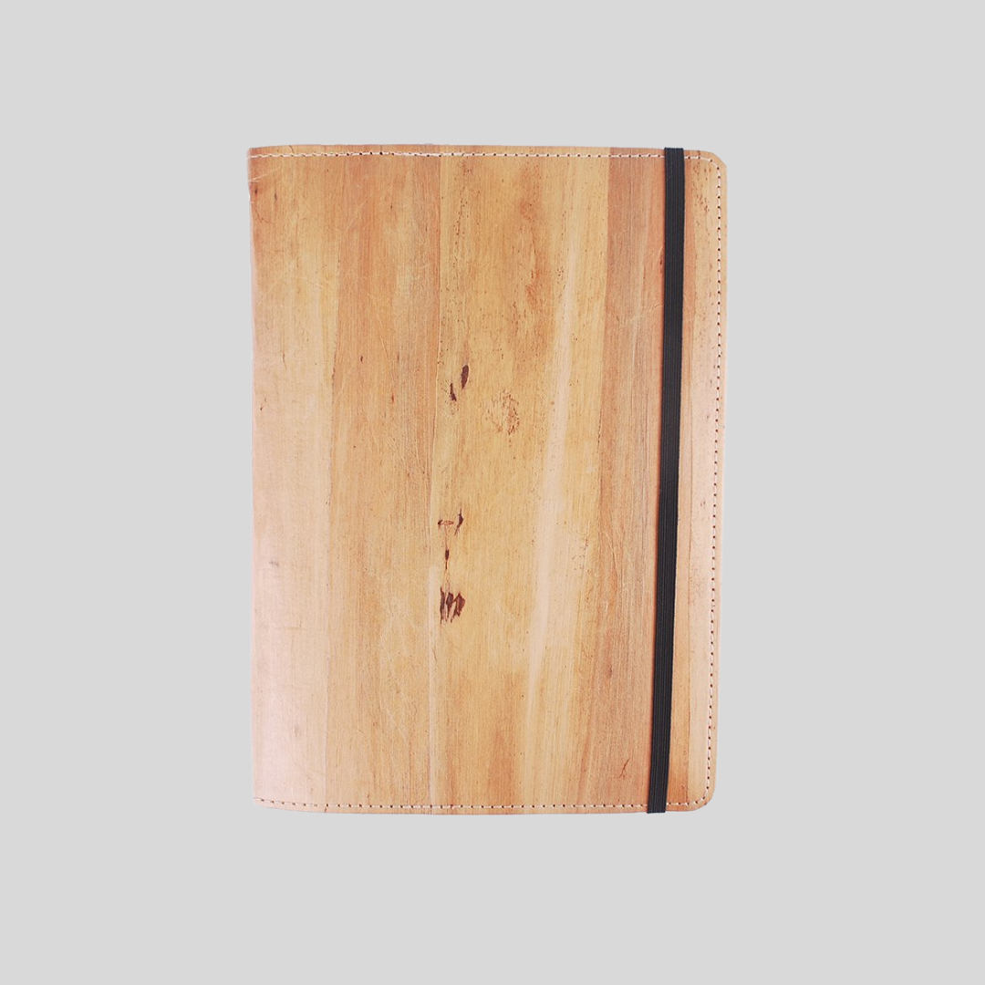 An ipad case made of vegan leather with a black garter, in front of a plain gray background.