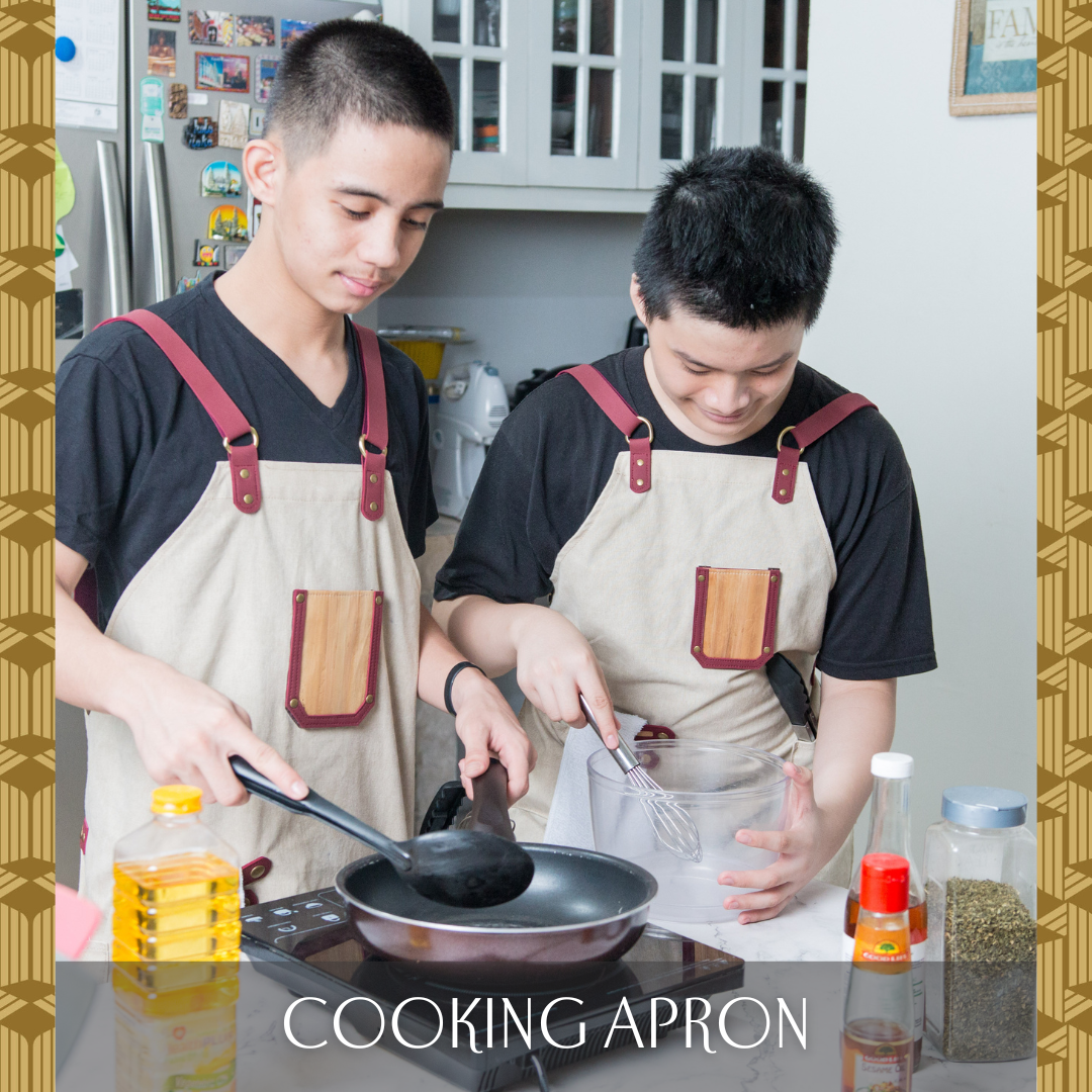 Two people cooking while wearing a white apron with a vegan leather pocket and red leather straps.