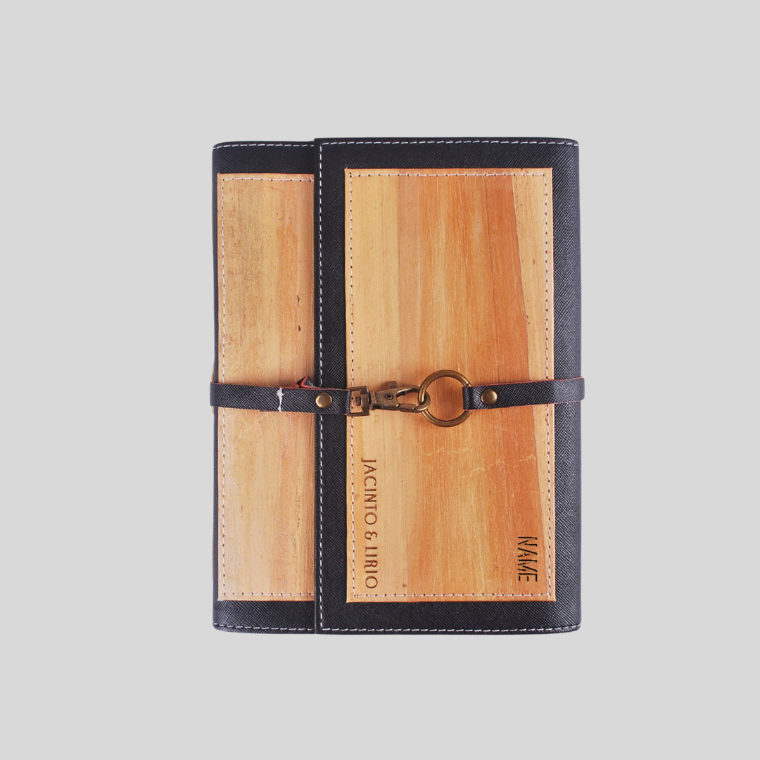 A journal with two flaps that cover it and is further closed by a metal hook  strap that wraps around it.