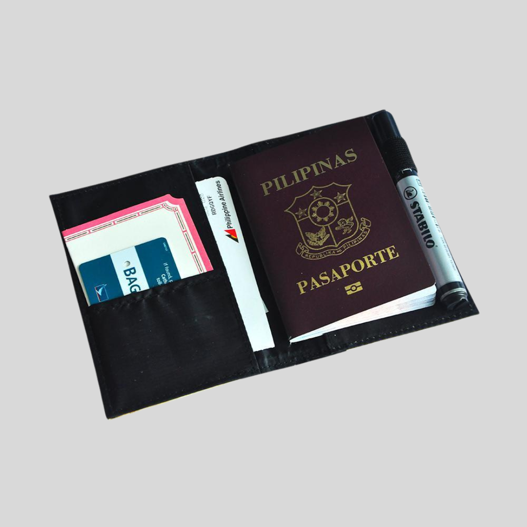 A black passport holder that contains a philippine passport, a black marker, and some boarding tickets.