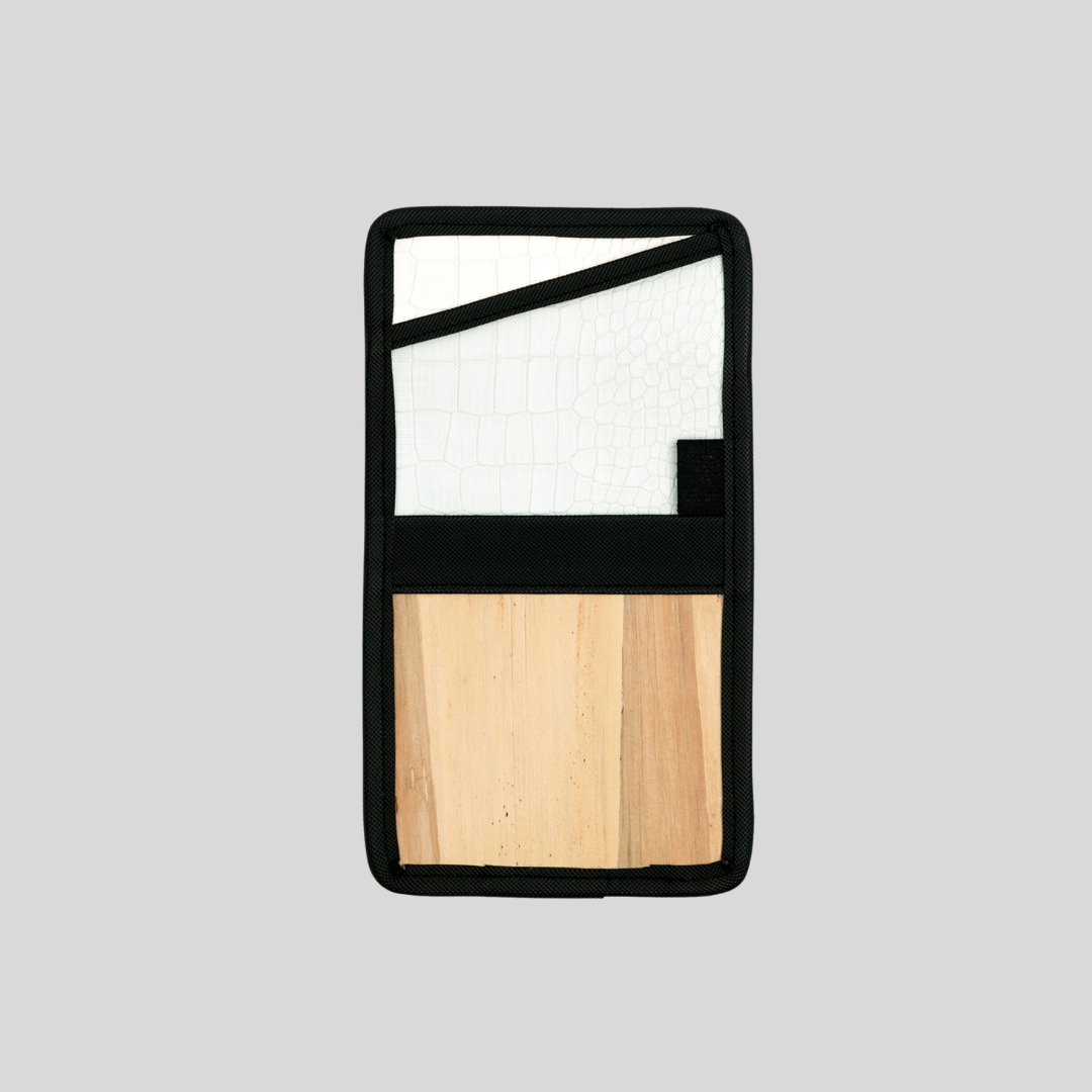 A passport holder that has faux white crocodile skin inside, a vegan leather exterior, and black hemming.