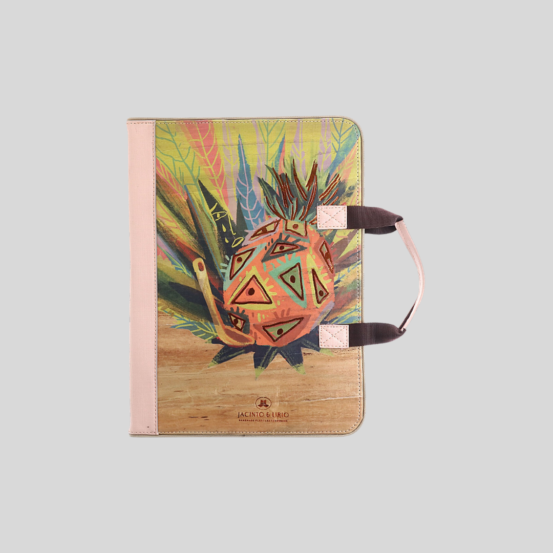 A vegan leather planner with a light pink colored spine and handle, with an abstract illustration of pineapple on its cover.