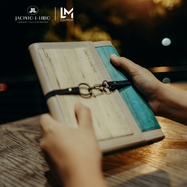 Two hands holding a teal and brown journal.