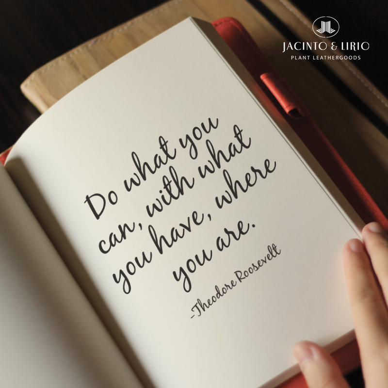 A red vegan leather notebook opened to a page that contains a quote from Theodore Roosevelt, written in stylish calligraphy.