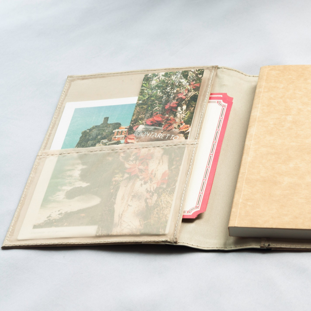 A beige journal with numerous paper compartments in its inner flap that houses multiple pictures and memorabilia.
