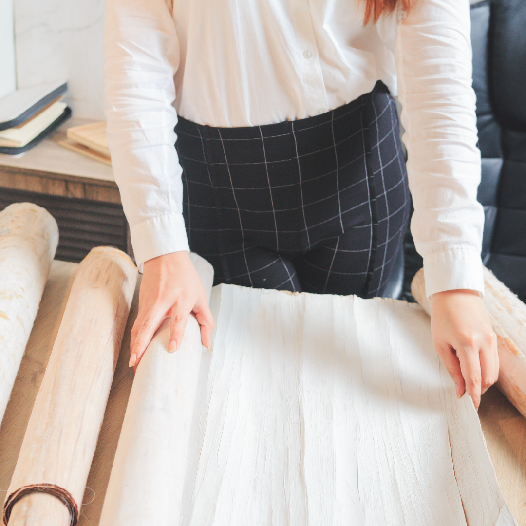 A woman rolling out a roll of white water hyacinth wallpaper
