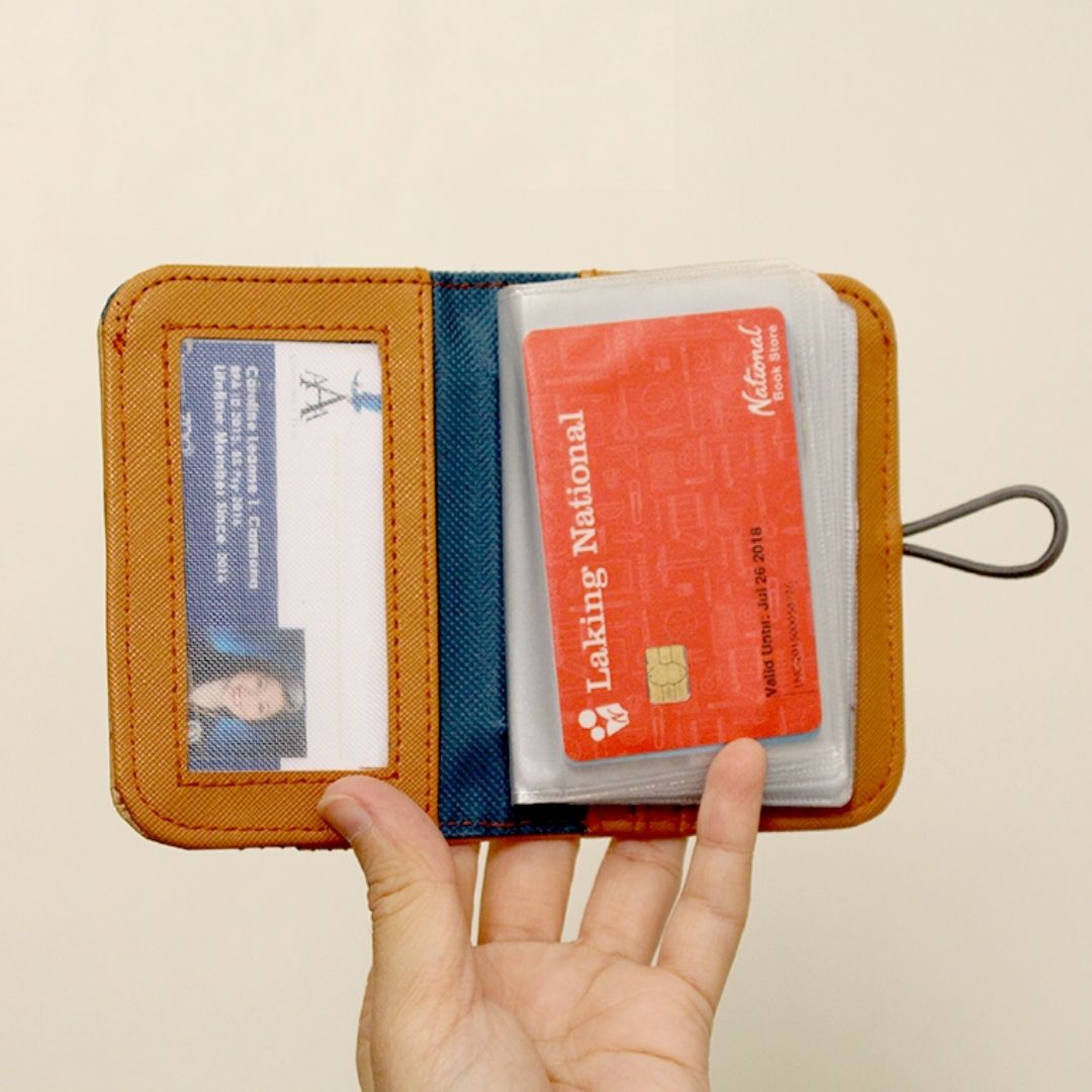 A hand holding up a orange vegan leather card wallet