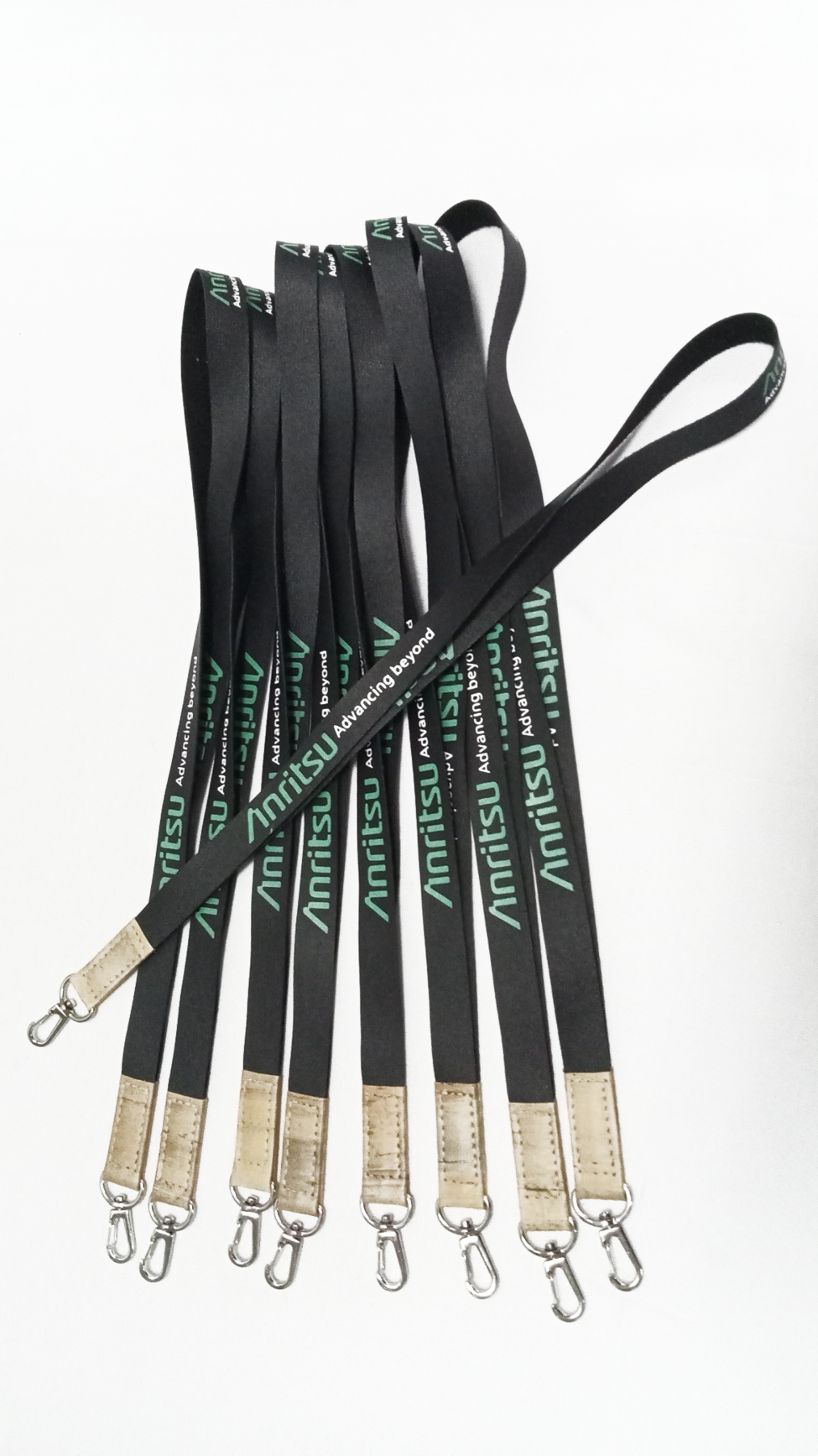 Group of black custom Anritsu lanyards with green logo, ideal for ID badges, corporate events, and promotional giveaways. Includes durable metal clips. Each lanyard featuring the green "Advancing Beyond" slogan, brown faux leather accents, and a silver swivel clip.
