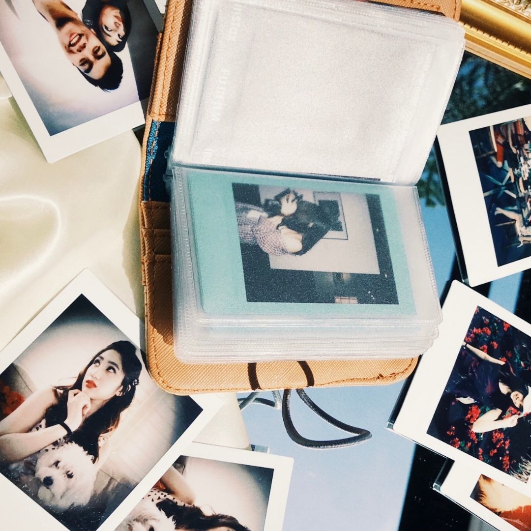 A bunch of polaroids stored inside the clear plastic pages of a card wallet