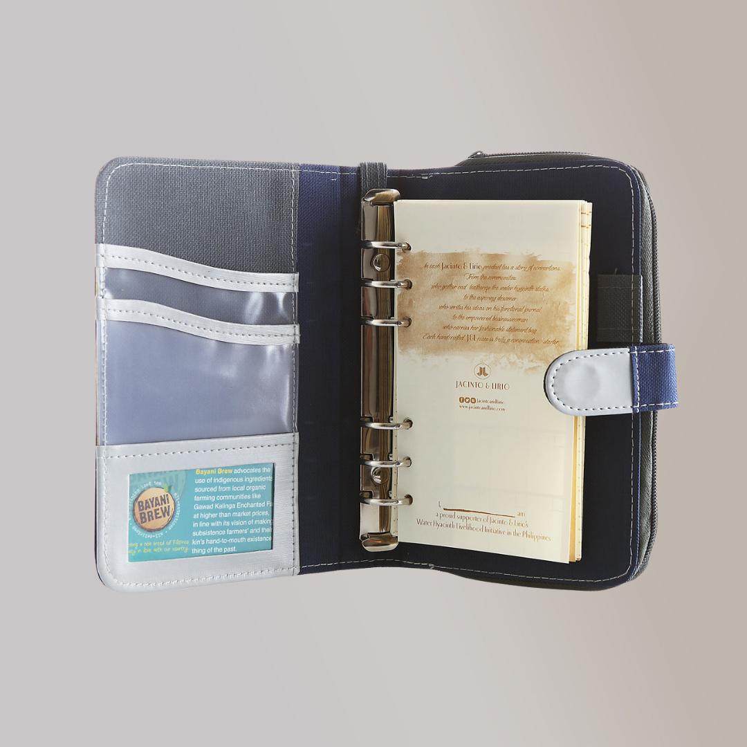 A blue leather notebook opened to its first page with writing on it and its inside flap which has card and picture compartments in clear plastic.