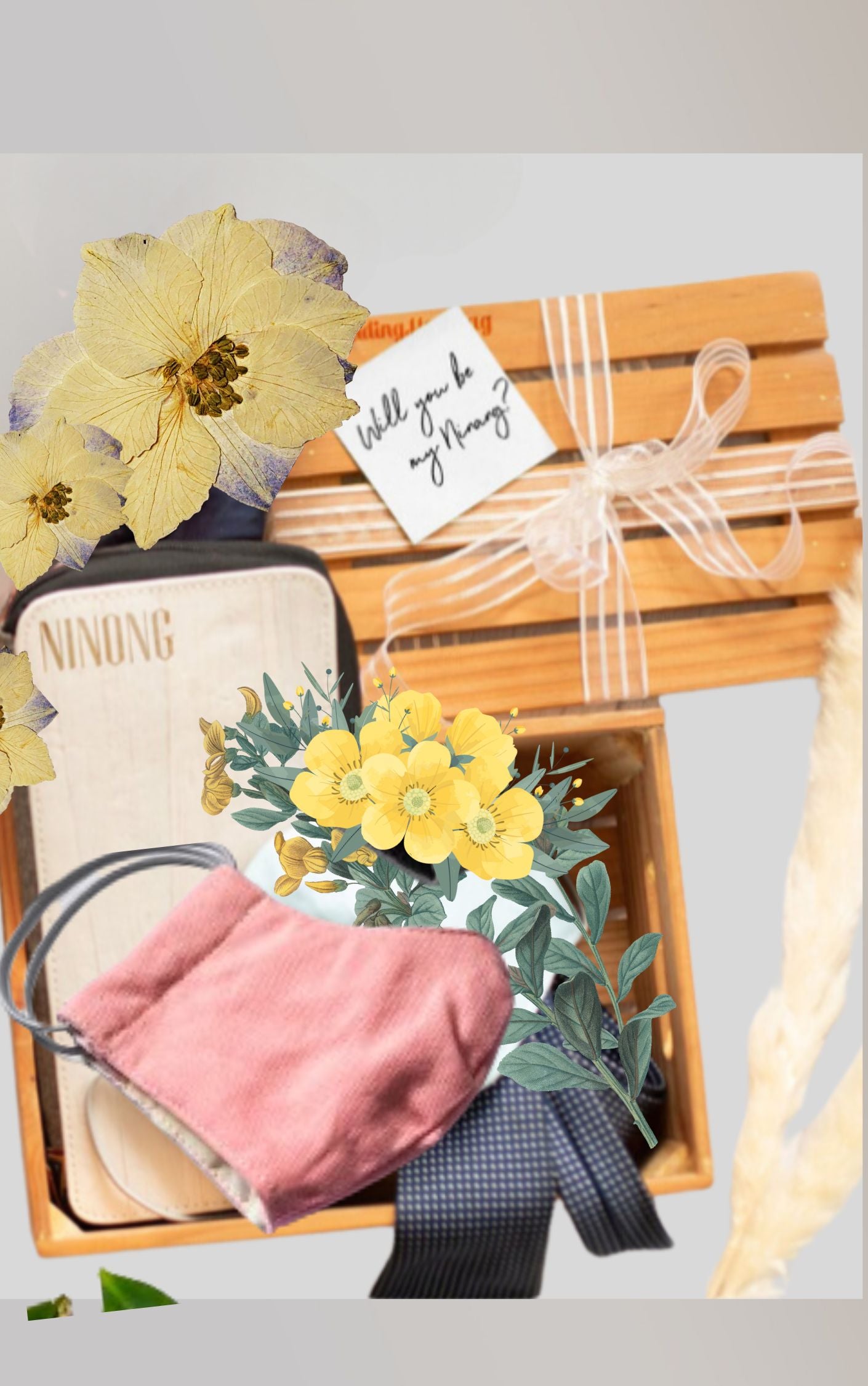 A gift set inside a wooden crate containing: a pastel pink travel wallet and notebook, and a light pink fabric mask, along with yellow flowers and blue ribbons for decoration.