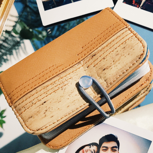 A brown vegan leather card wallet with button and strap closure.