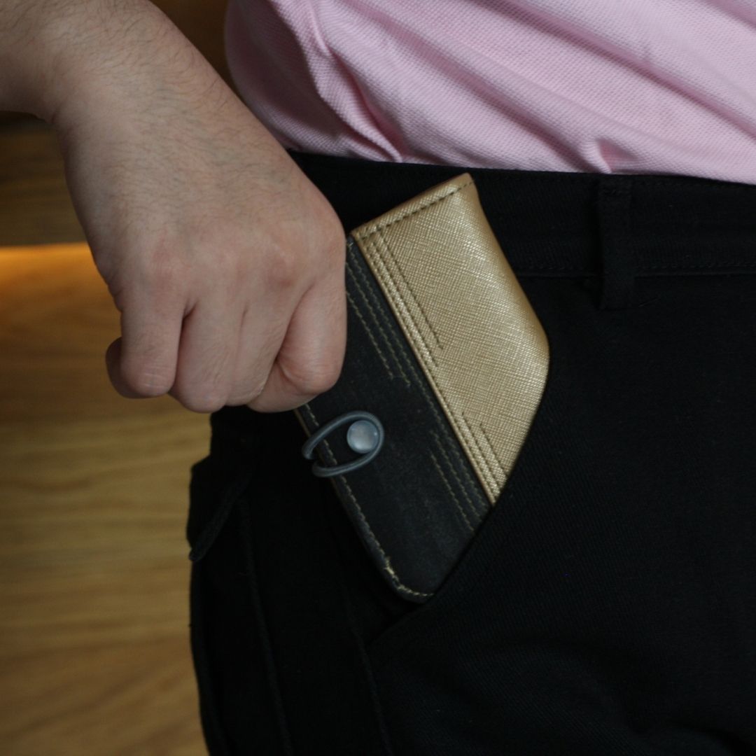 A person tucking in their dual-colored vegan leather card wallet into their pocket