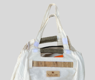 A white tote bag with brown leather accents on it.