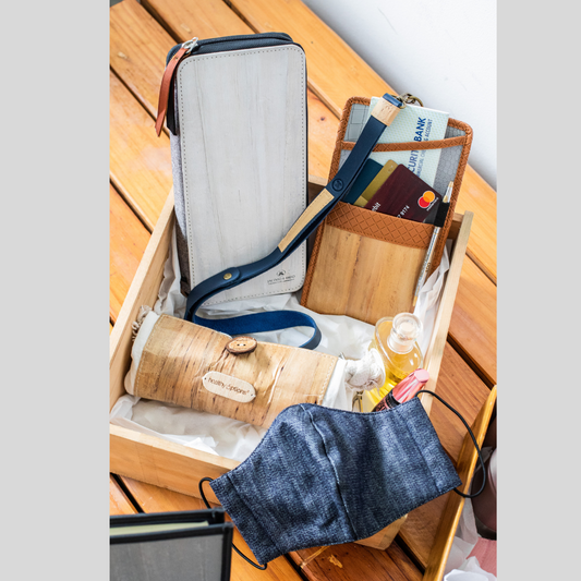 A gift set of multi-use vegan leather products inside a wooden crate, such as an ID lanyard and passport holder.