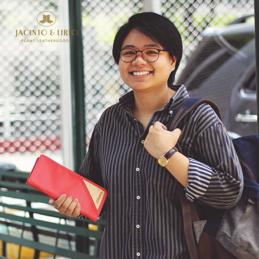 A woman happily carrying a red vegan leather wallet that has her name laser engraved into the corner of the wallet.