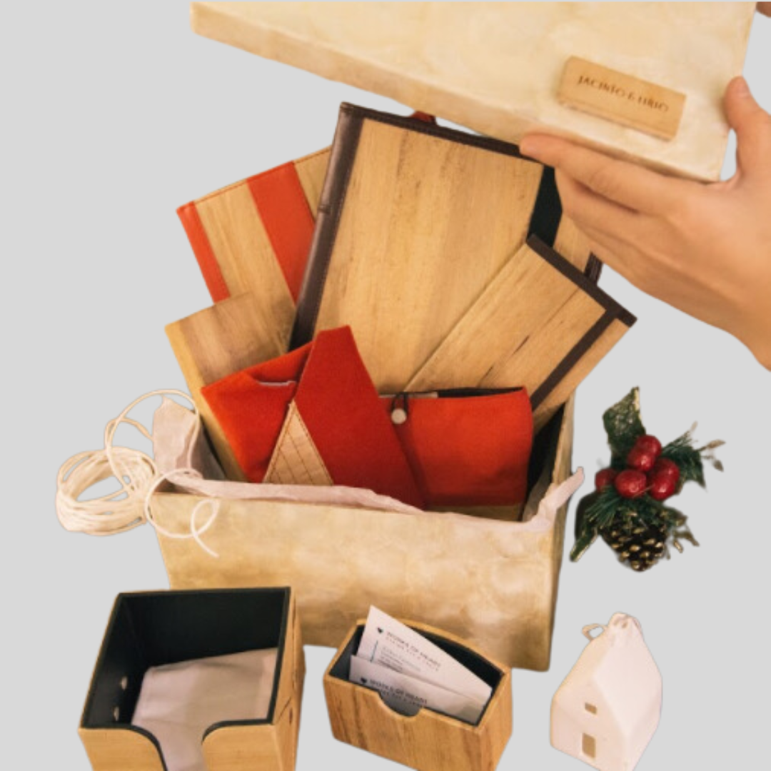 Jacinto & Lirio Vegan Leather Office products in colors red and beige arranged in a box with christams decor around it.