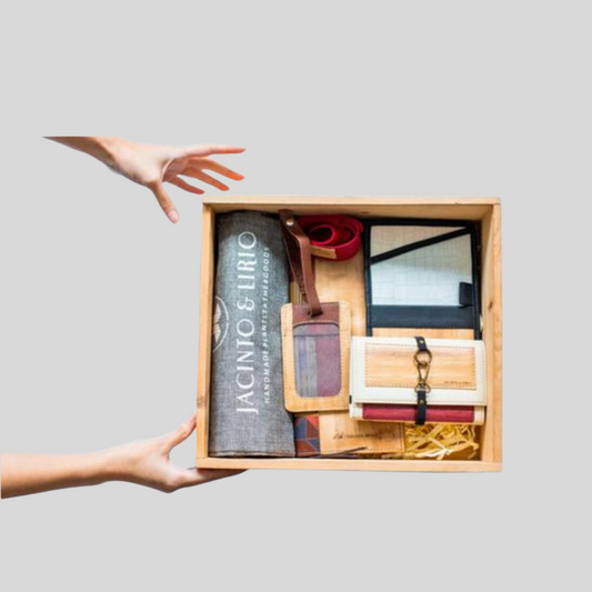 A wooden box filled with vegan leather products such as a wallet, an ID lanyard, and other goods.