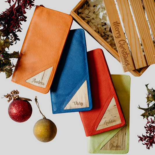 Four color variations of a rectangular vegan leather wallet, with christmas tree decoration balls laying beside them.