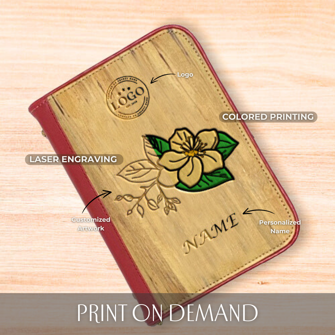 A vegan leather notebook with a red spine and hem, adorning a colored laser engraving of a flower on its cover, along with an engraved custom logo and name.